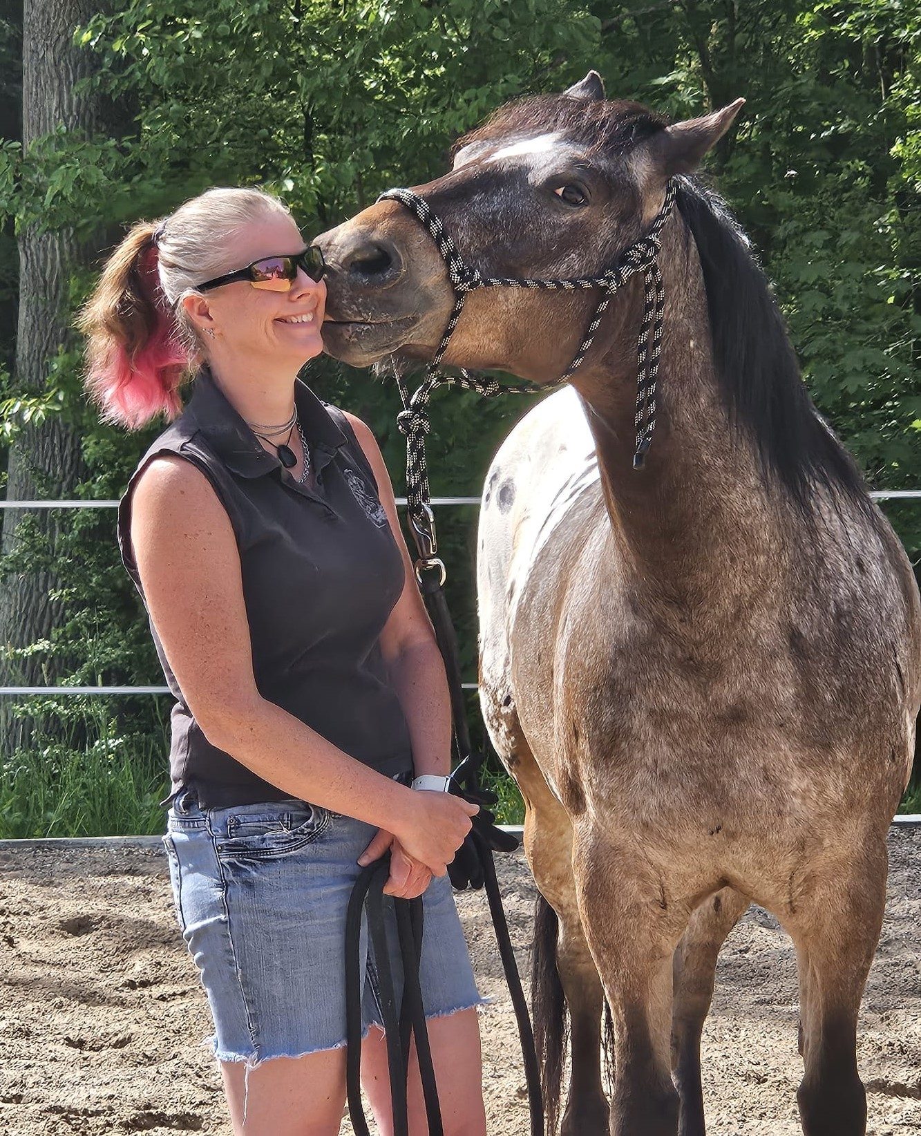 Ich stehe lächelnd neben einem Appaloosa der mein Gesicht mit den Lippen berührt als würde er mir einen Kuss geben